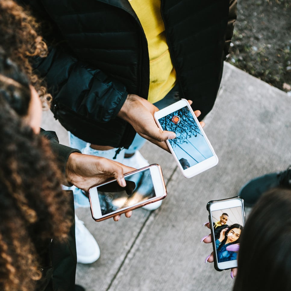 En grupp människor som står runt varandra och håller i mobiltelefoner.