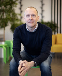 En man sitter på en grön stol i ett rum.