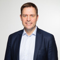 En man i blå kostym och vit skjorta.
