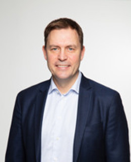 En man i blå kostym och vit skjorta.