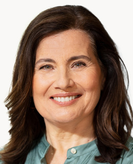 En kvinna i grön skjorta som ler mot kameran.