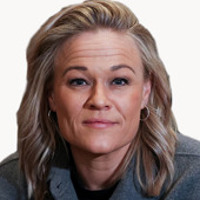 En kvinna med blont hår som bär en grå jacka.
