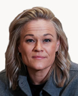 En kvinna med blont hår som bär en grå jacka.