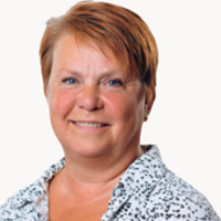 En kvinna med rött hår klädd i en blå och vit skjorta.