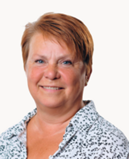 En kvinna med rött hår klädd i en blå och vit skjorta.