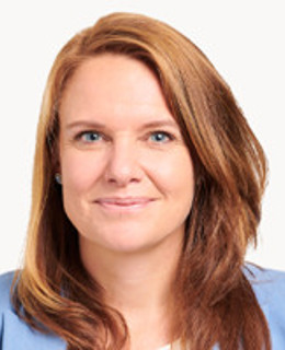 En kvinna i blå jacka och vit skjorta.