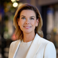 En kvinna i vit kostym står framför en byggnad.