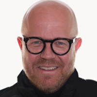 En man med skalligt huvud som bär glasögon.