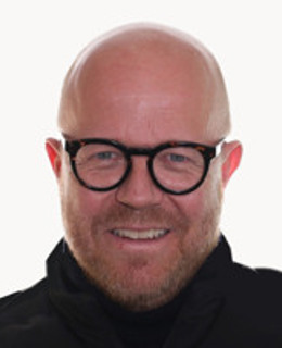 En man med skalligt huvud som bär glasögon.