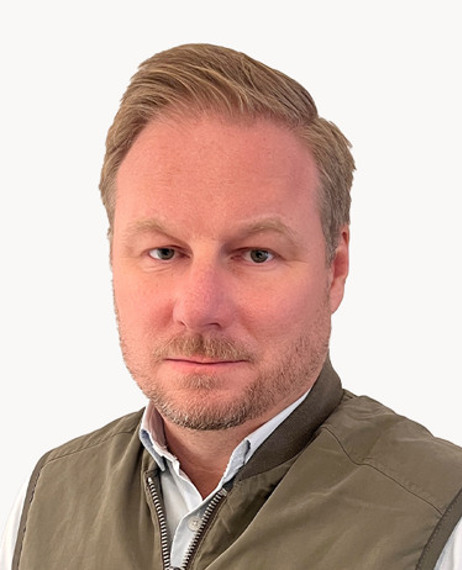 En man i väst poserar för att bli fotograferad.