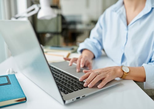 En kvinna sitter vid ett skrivbord och använder en bärbar dator.