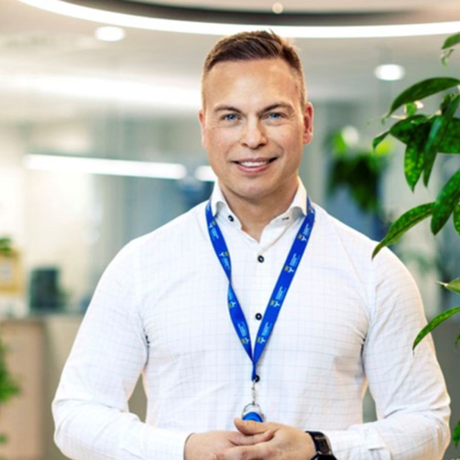 En man i vit skjorta håller i ett blått nyckelband.