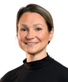 En kvinna i svart skjorta och bruna byxor.
