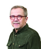 En man med glasögon som står framför en vit bakgrund.