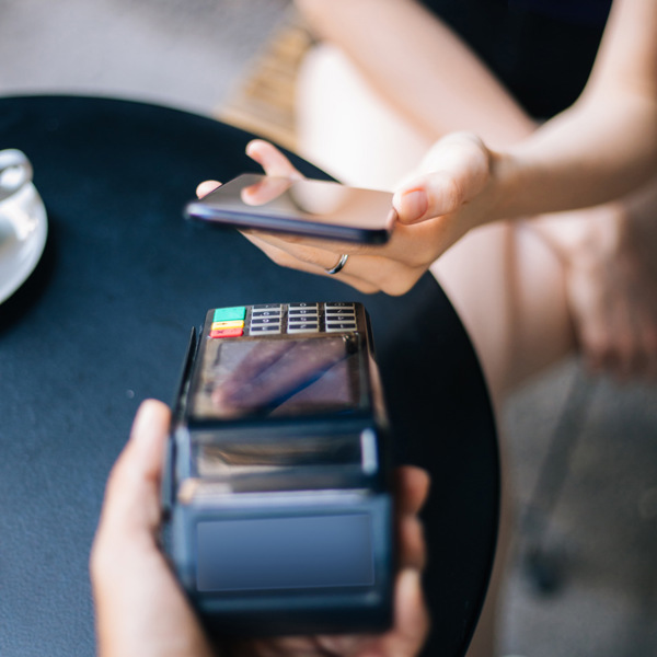 En person som sitter vid ett bord och håller i en mobiltelefon.