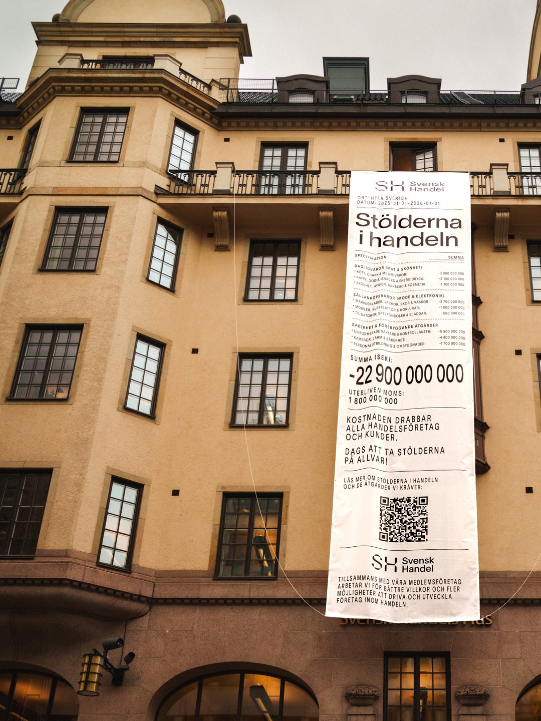 En hög byggnad med en skylt som hänger på sidan.