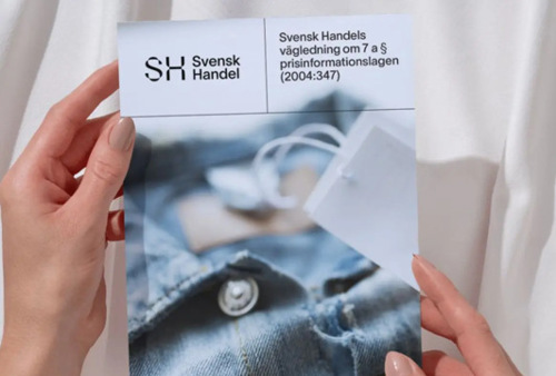 En person som håller upp en tidning med en bild av en skjorta på.