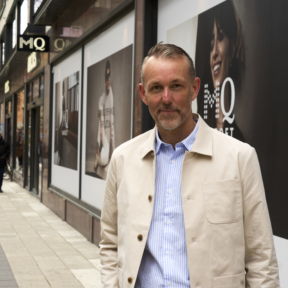 En man som står på en trottoar framför en butik.