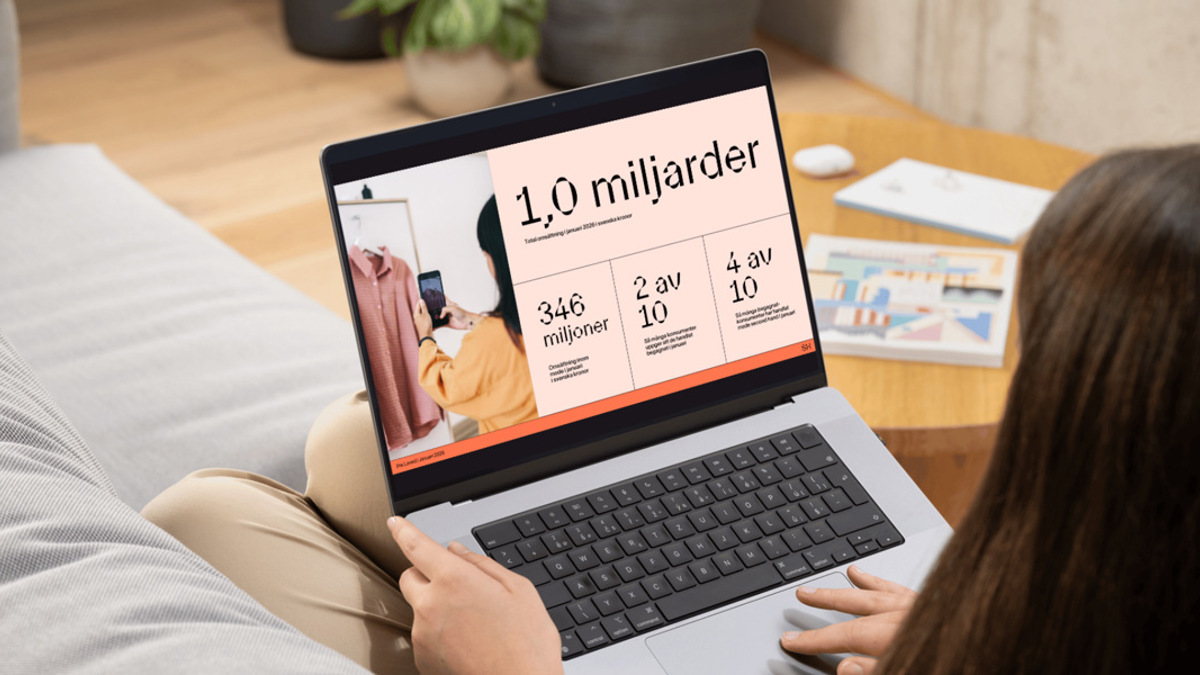 En kvinna sitter i en soffa och använder en bärbar dator.