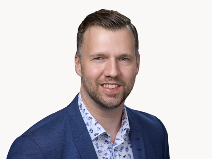 En man i en blå jacka ler mot kameran.