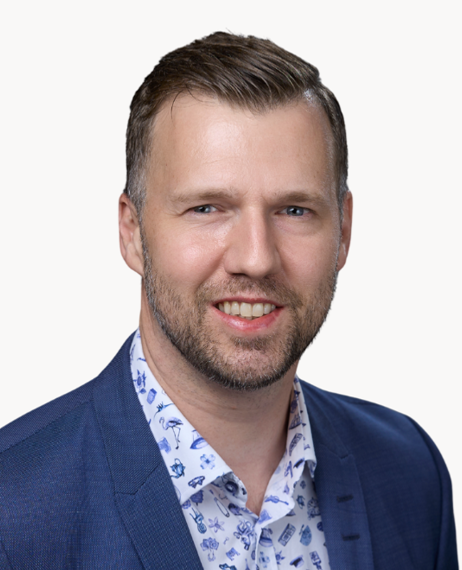 En man i en blå jacka ler mot kameran.