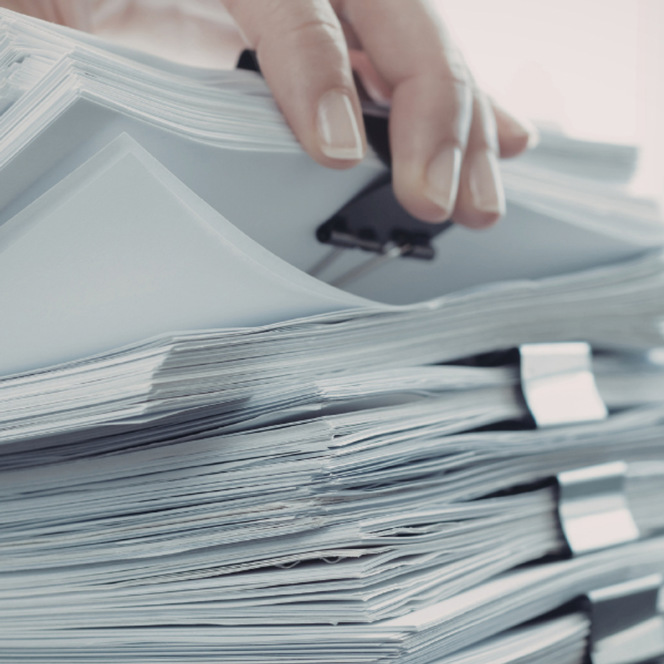 En person håller i en bunt papper.