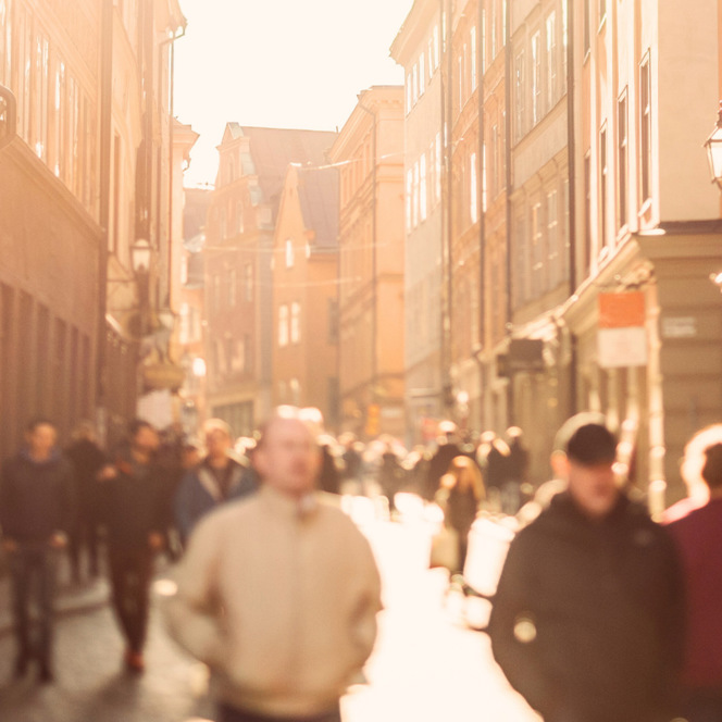 En grupp människor som går längs en gata bredvid höga byggnader.