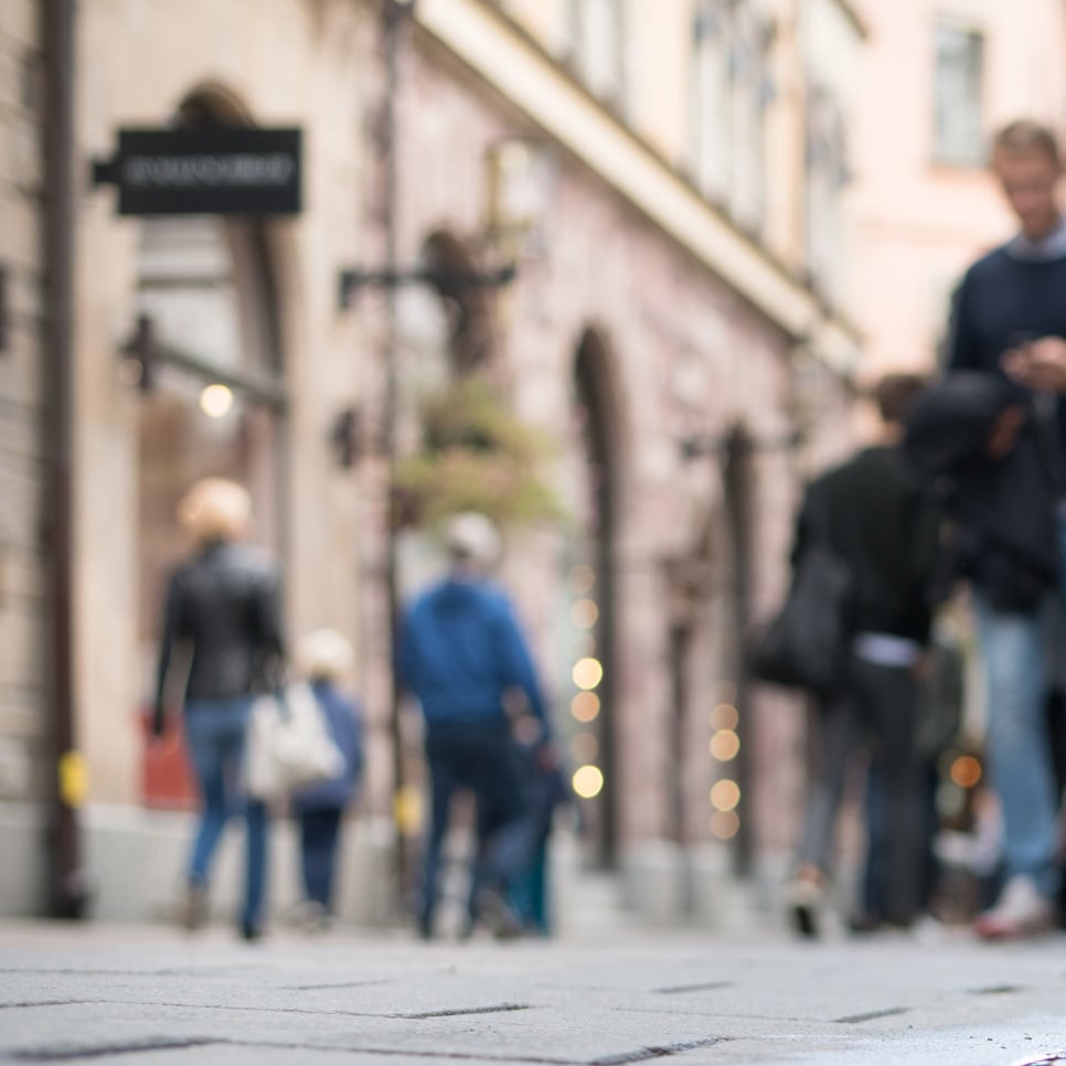 En grupp människor som går längs en gata bredvid en vattenpöl.