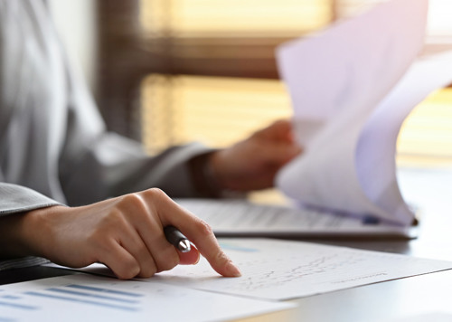 En person som sitter vid ett skrivbord med papper och penna.