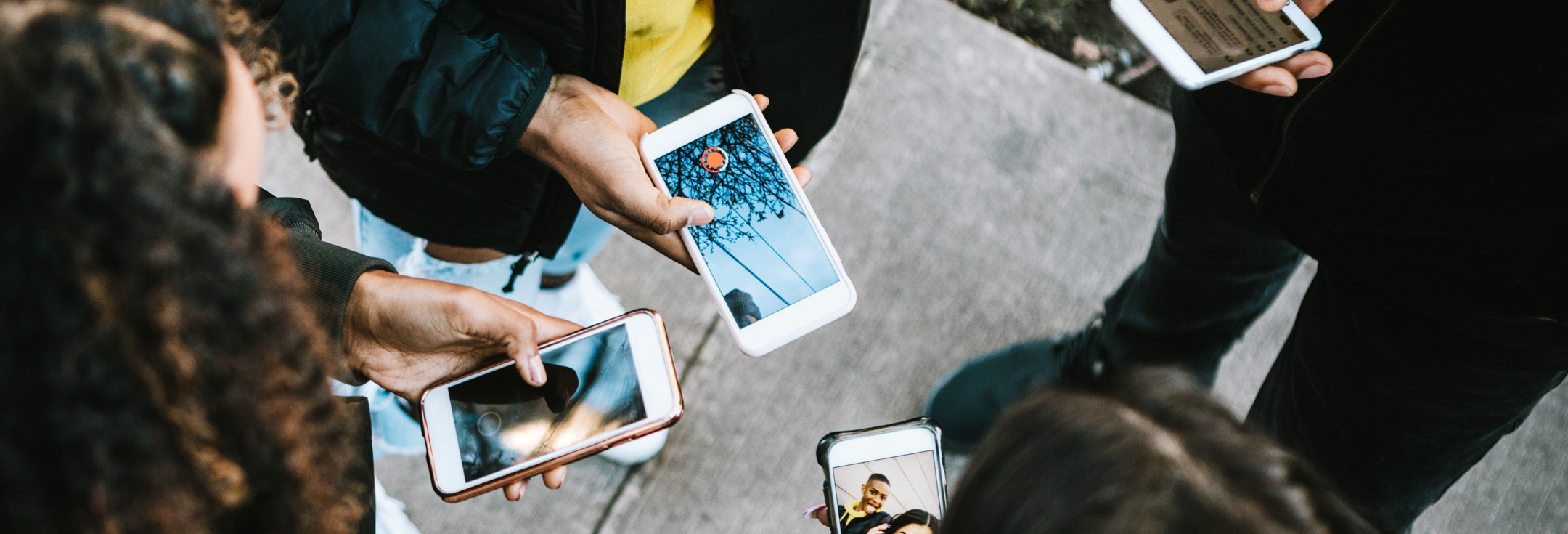 En grupp människor som står runt varandra och håller i mobiltelefoner.