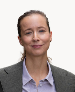 En kvinna i affärskostym ler mot kameran.