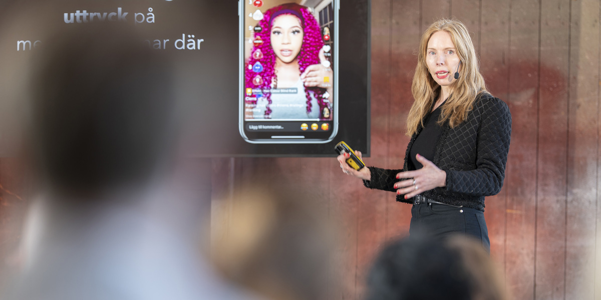 En kvinna som h&aring;ller en presentation f&ouml;r en grupp m&auml;nniskor.