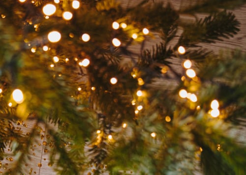 Två inslagna julklappar under en julgran med ljus.