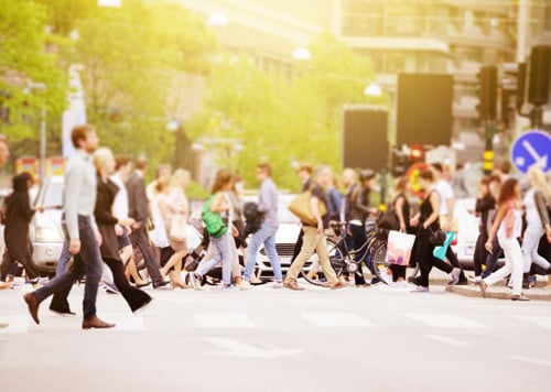 En folkmassa som går över en gata.