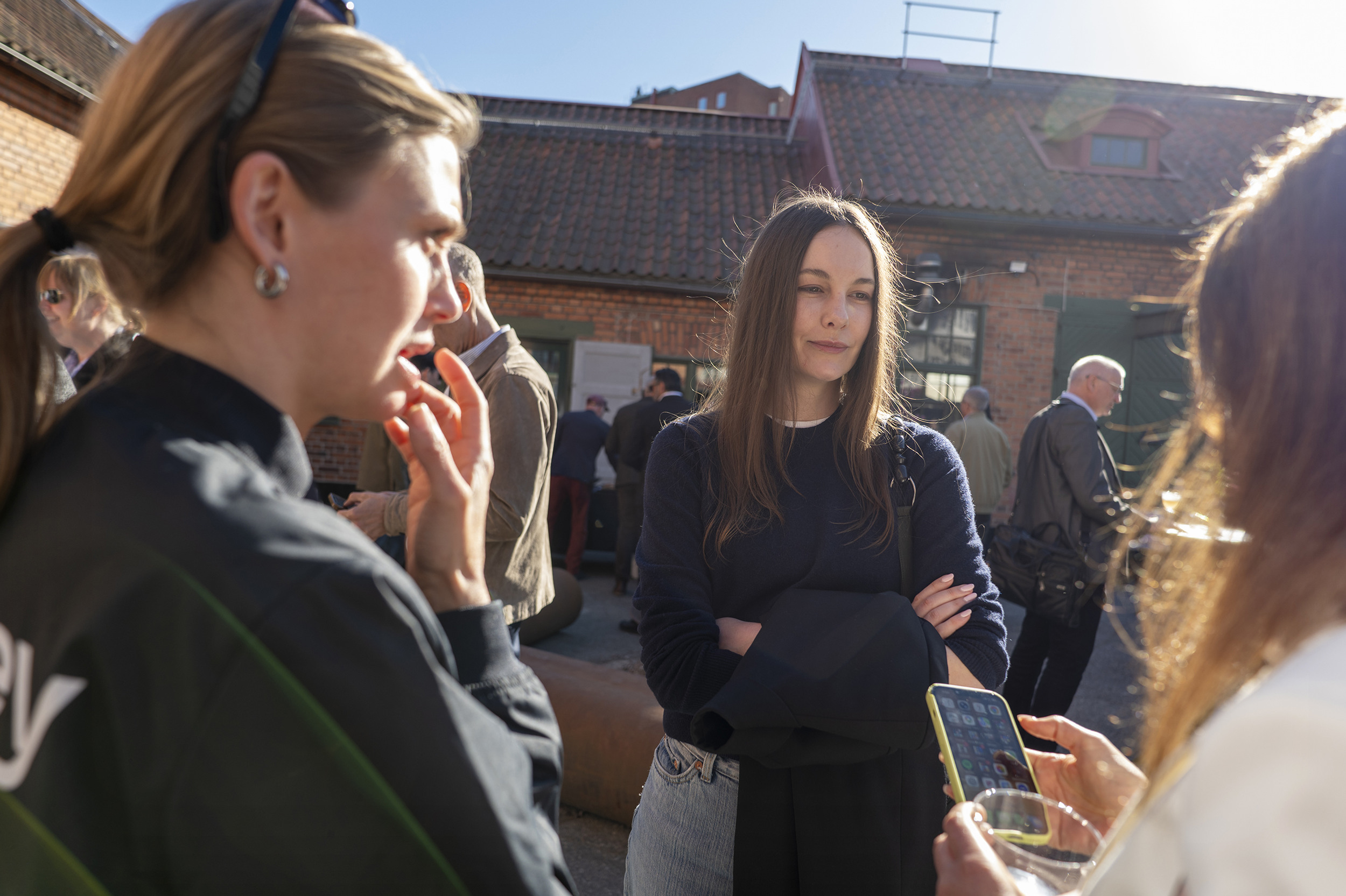 En grupp kvinnor som st&aring;r runt varandra och pratar i mobiltelefon.