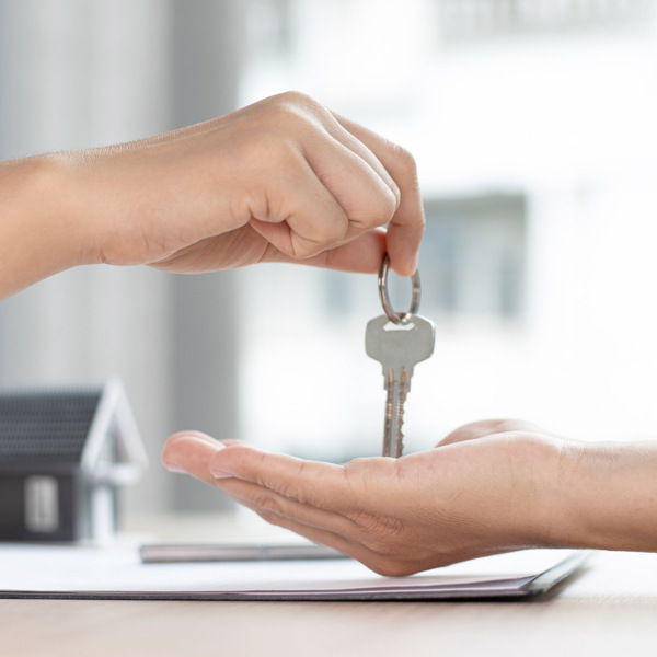En person som överlämnar en husnyckel till en annan person.