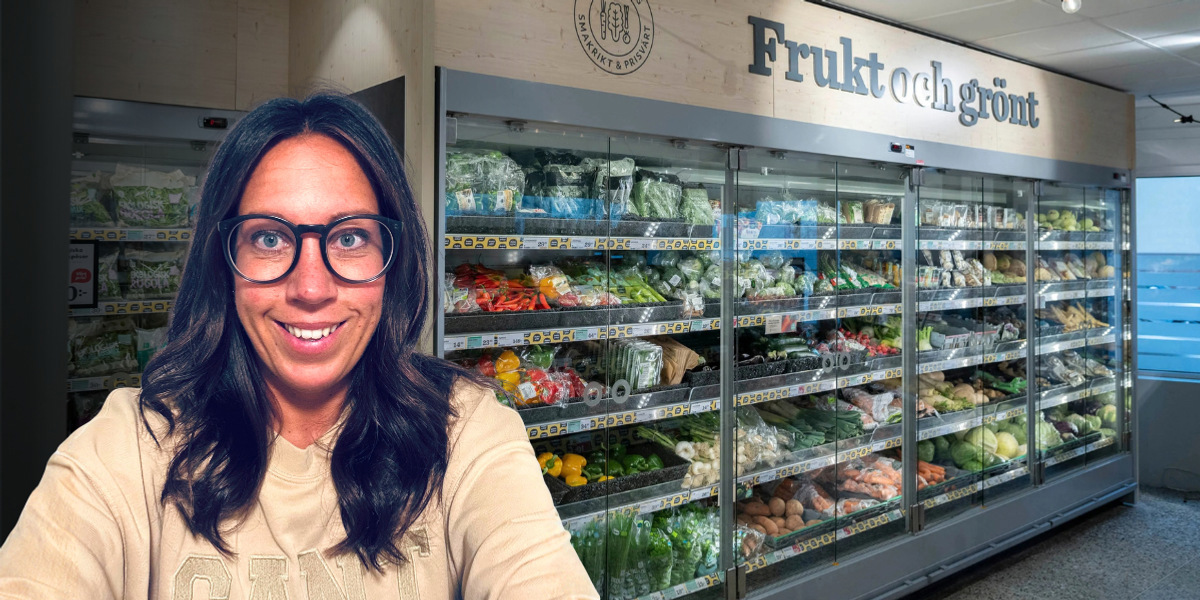 En kvinna med glasögon som står framför en frukt- och grönsaksdisk.