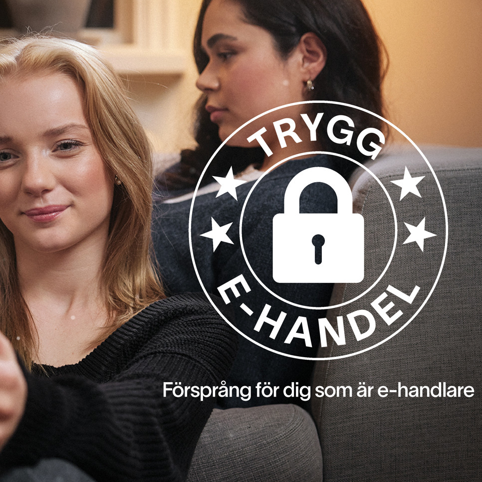 Två kvinnor sitter i en soffa och tittar på en mobiltelefon.