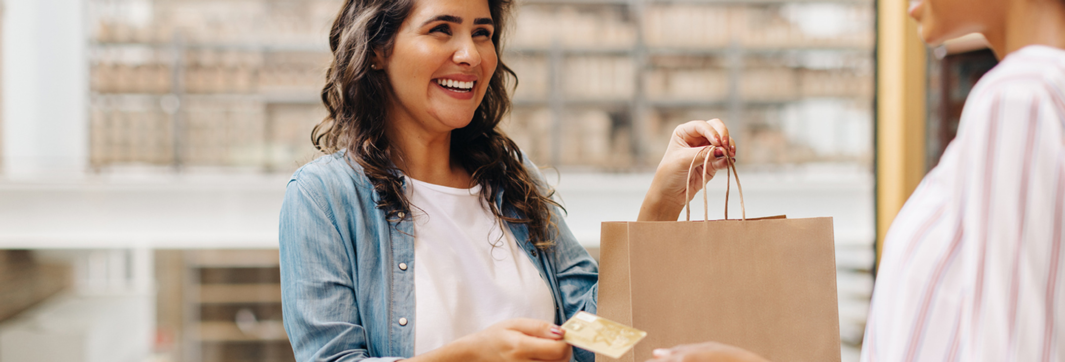 En kvinna håller i en shoppingväska och ett kreditkort.