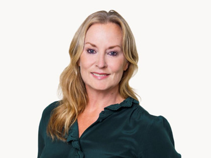 En kvinna i grön skjorta poserar för en bild.