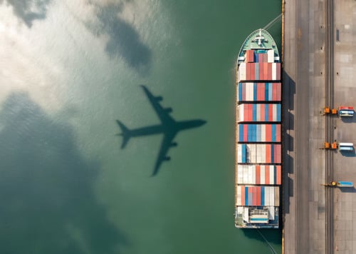 Ett flygplan flyger över ett stort containerfartyg.