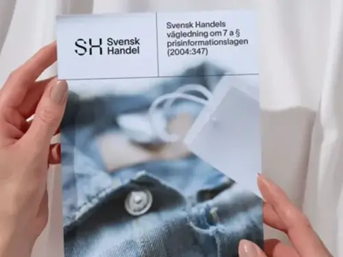 En person som håller upp en tidning med en bild av en skjorta på.