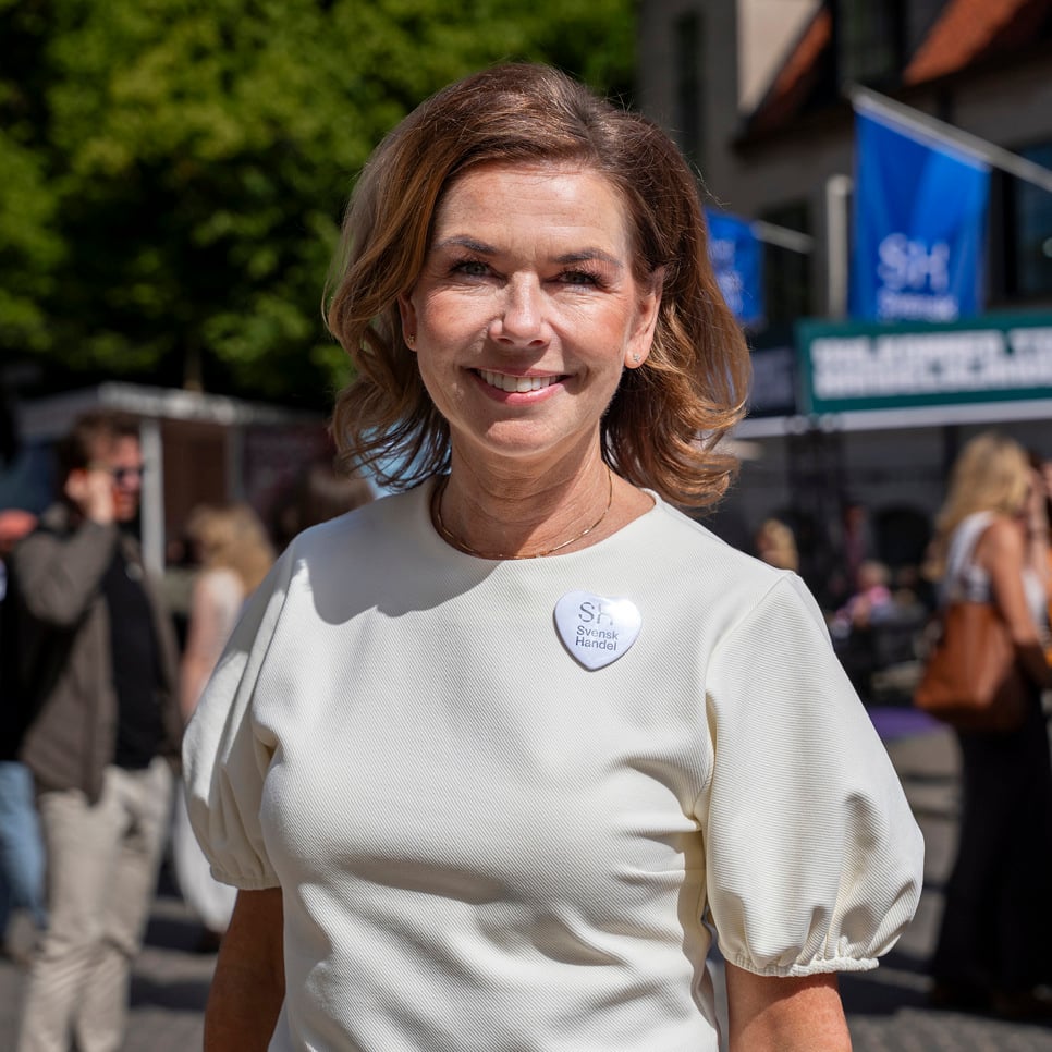 En kvinna i en vit klänning som går längs en gata.