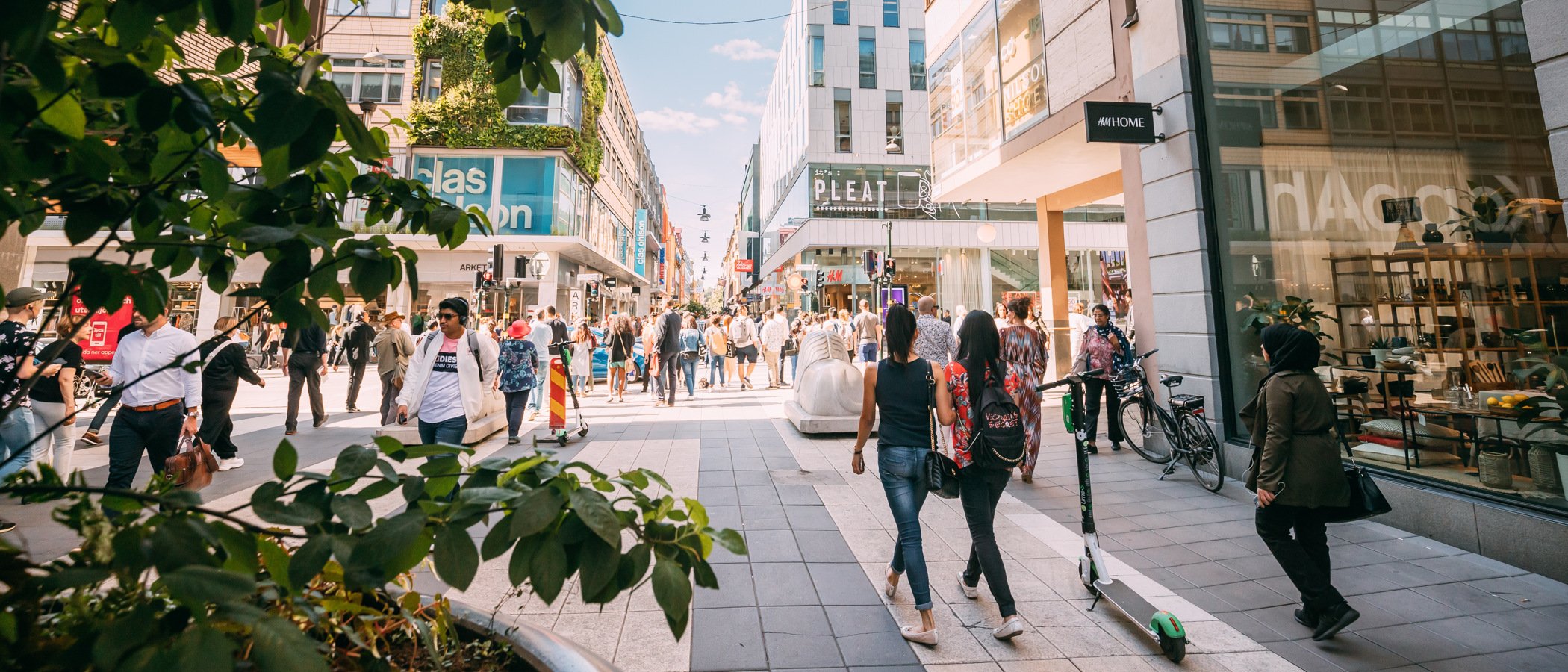 En grupp människor som går längs en gata bredvid höga byggnader.