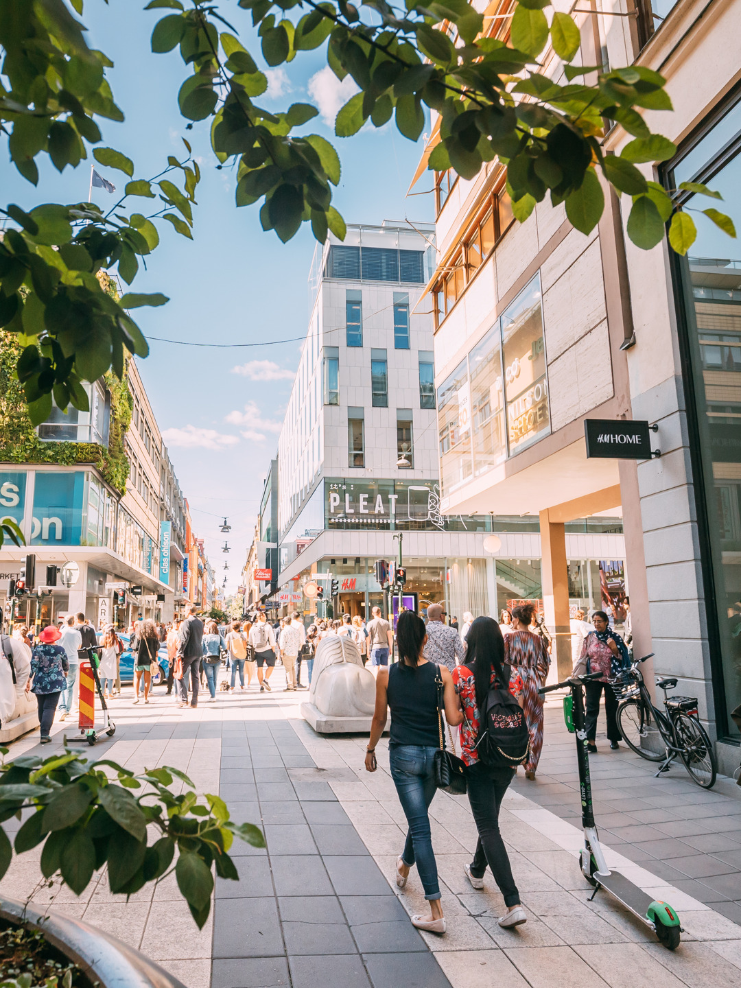 En grupp människor som går längs en gata bredvid höga byggnader.