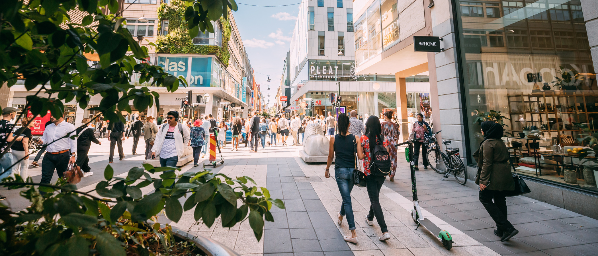 En grupp människor som går längs en gata bredvid höga byggnader.