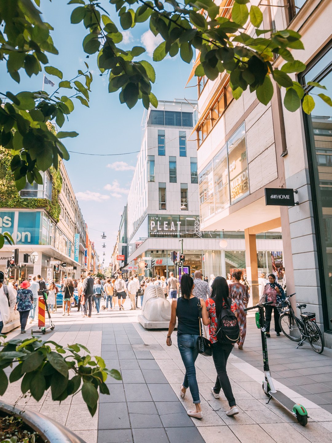 En grupp människor som går längs en gata bredvid höga byggnader.