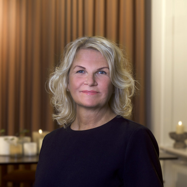 En kvinna i svart topp står i ett vardagsrum.