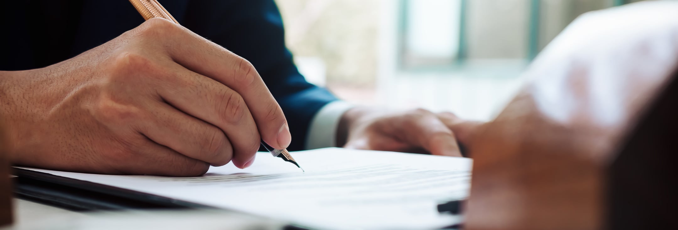 En närbild på en person som skriver på ett papper.