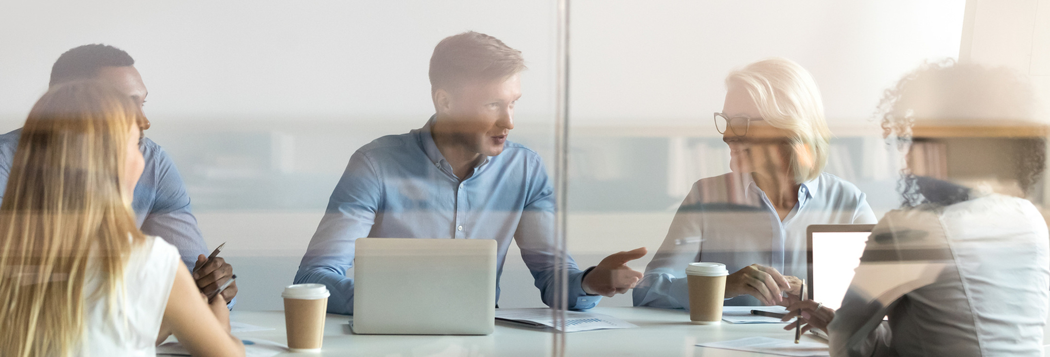 En grupp människor som sitter vid ett bord med bärbara datorer.